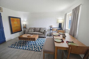 A living room with a sofa, coffee table, and dining area with chairs and plates. - 2-Bedroom in Glendale near Westgate and Stadium with AC, Pet Friendly! (Glendale)