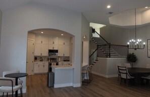 A modern kitchen with white cabinets, a central island, and a dining area with a round table and chairs. - Spacious luxurious 4-bedroom  4-full bathroom house easy access to IH-35 (Kyle)