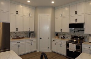 Una cucina con mobili bianchi, frigorifero in acciaio inossidabile, microonde e forno.