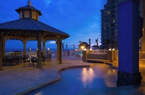 A pool area with a gazebo, lounge chairs, and a view of the ocean at dusk. - Spacious 2-bedroom beachfront condo in Orange Beach with private jacuzzi tubs (Orange Beach)