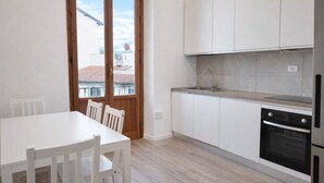 A modern kitchen with white cabinets, a sink, and an oven. There is a dining table with chairs. - Spacious & Comfortable Stay in Florence - 4 Guests (Firenze)