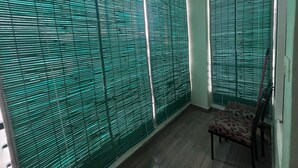 A room with a patterned chair, a window with blinds, and a door. - Premium 1BHK Gachibowli -Walk to AIG (Hyderabad)