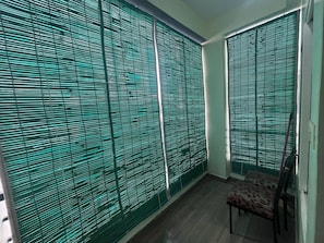 A room with a patterned chair, a window with blinds, and a door. - Premium 1BHK Gachibowli -Walk to AIG (Hyderabad)