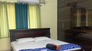 A hotel room with a bed, a wardrobe, an air conditioning unit, and curtains. - Premium 1BHK Gachibowli -Walk to AIG (Hyderabad)