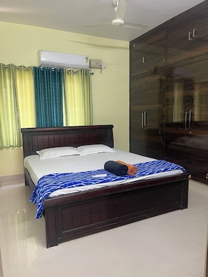 A hotel room with a bed, a wardrobe, an air conditioning unit, and curtains. - Premium 1BHK Gachibowli -Walk to AIG (Hyderabad)