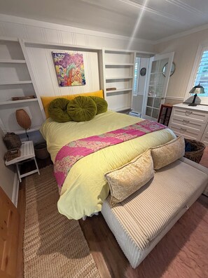 Een slaapkamer met een bed, een bankje, een dressoir en een raam.