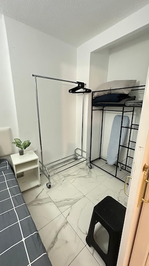 A compact room with a bunk bed, a metal drying rack, a small white nightstand with a plant, and a black stool. - Tenerife Beach Front & Sea View (Los Cristianos)