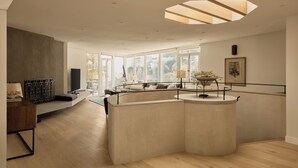 Ein modernes Wohnzimmer mit einer gebogenen Sitzecke, einem Flachbildfernseher und einem Esstisch mit einer Pflanze.