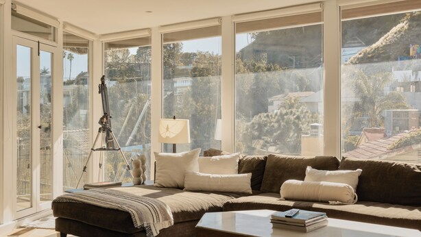 Ein modernes Wohnzimmer mit großem Fenster, einem Stativ und einer Couch.