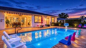En swimmingpool med liggestole, en basketballkurv og et hus med terrasse.