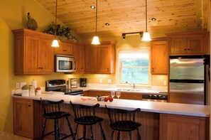 Una cocina con gabinetes de madera, un refrigerador de acero inoxidable, un microondas y una isla grande con taburetes de bar.