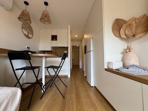 A modern kitchen with white cabinets, a wooden countertop, and two black chairs. - Tiny House de Romy, 4 personnes, pieds dans l'eau (Le Cap d'Agde)