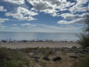 A beach with pebbles, rocks, and sparse vegetation. - Tiny House de Romy, 4 personnes, pieds dans l'eau (Le Cap d'Agde)