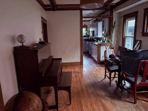 Ein Zimmer mit einem hölzernen Klavier, einem Globus und einem Schreibtisch mit einem Stuhl.