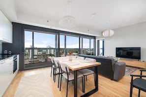 Un apartamento moderno con comedor, cocina y sala de estar, que cuenta con ventanas amplias y vistas a la ciudad.