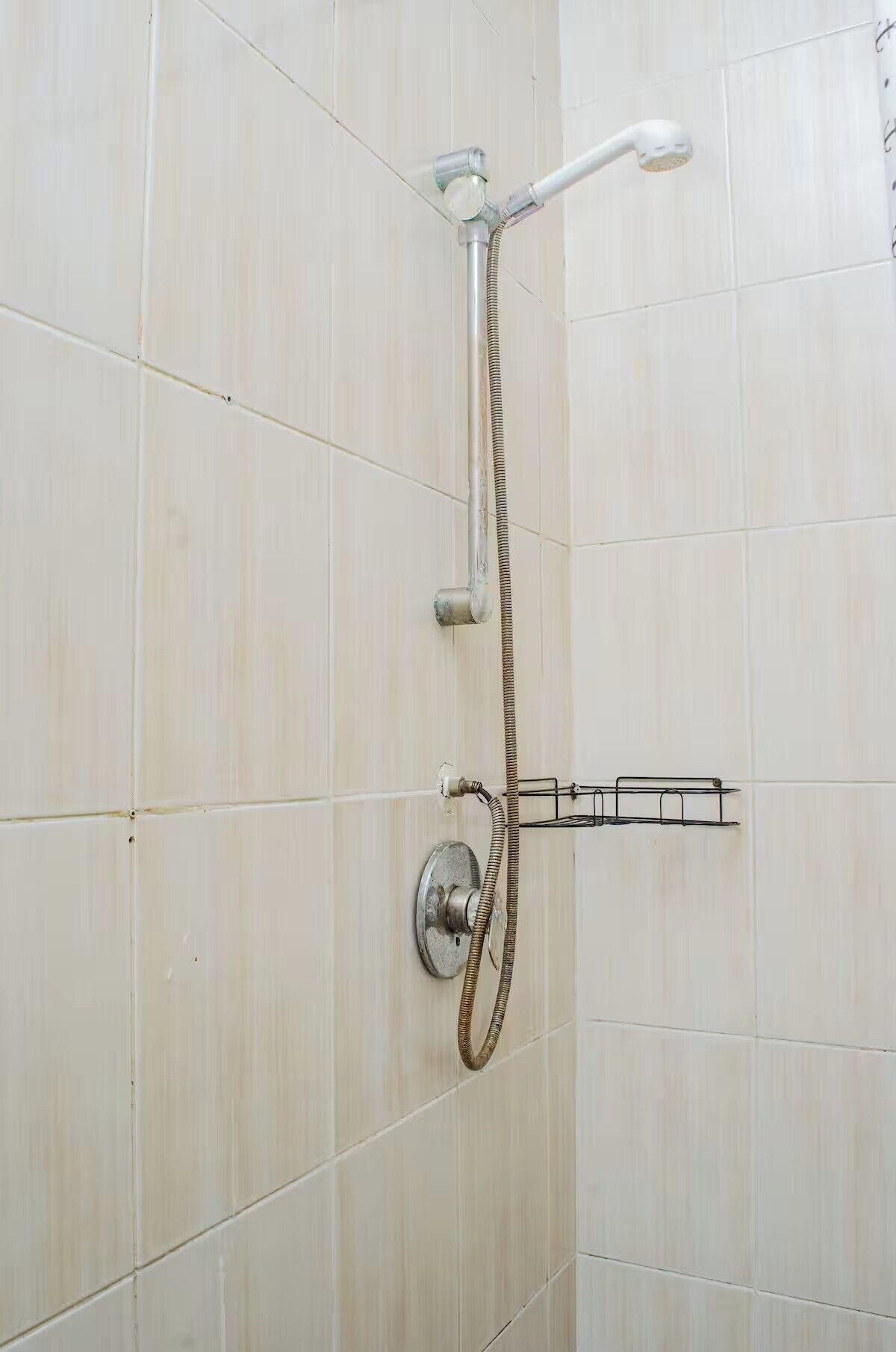 A shower with a handheld showerhead and a fixed showerhead, both mounted on a wall.