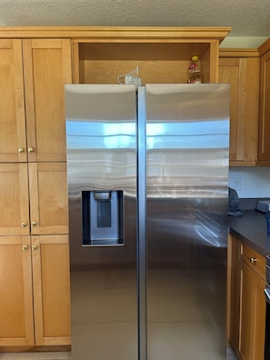 Ein Edelstahl-Kühlschrank mit Wasserspender, Holzschränke und eine Arbeitsplatte mit einem Toaster.