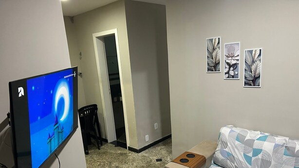 Een kamer met een bed, een televisie en een deur naar een andere kamer.