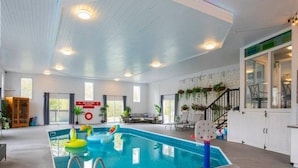 Een binnenzwembad met een reddingsboei, een bord met de tekst 'NO DIVING' en een trap die naar een balkon leidt.