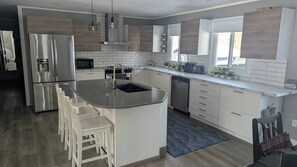 Una cocina moderna con una isla central, electrodomésticos de acero inoxidable y vistas al exterior.