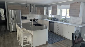 A modern kitchen with a central island, stainless steel appliances, and a view of the outdoors. - Indoor Pool! Hot Tub! Sauna! at the Blue Haven! (Trent Lakes)