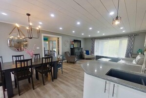 Una cocina moderna con isla integrada, zona de comedor con sillas y sala de estar con sofá.