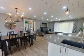 Una cocina moderna con isla integrada, zona de comedor con sillas y sala de estar con sofá.