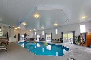 An indoor swimming pool with a clear ceiling, windows, and a wooden deck area. - Indoor Pool! Hot Tub! Sauna! at the Blue Haven! (Trent Lakes)