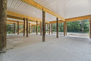 An open interior space with wooden beams and columns, a concrete floor, and a view of the outdoors.