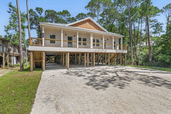 A two-story wooden house with a balcony, surrounded by trees.