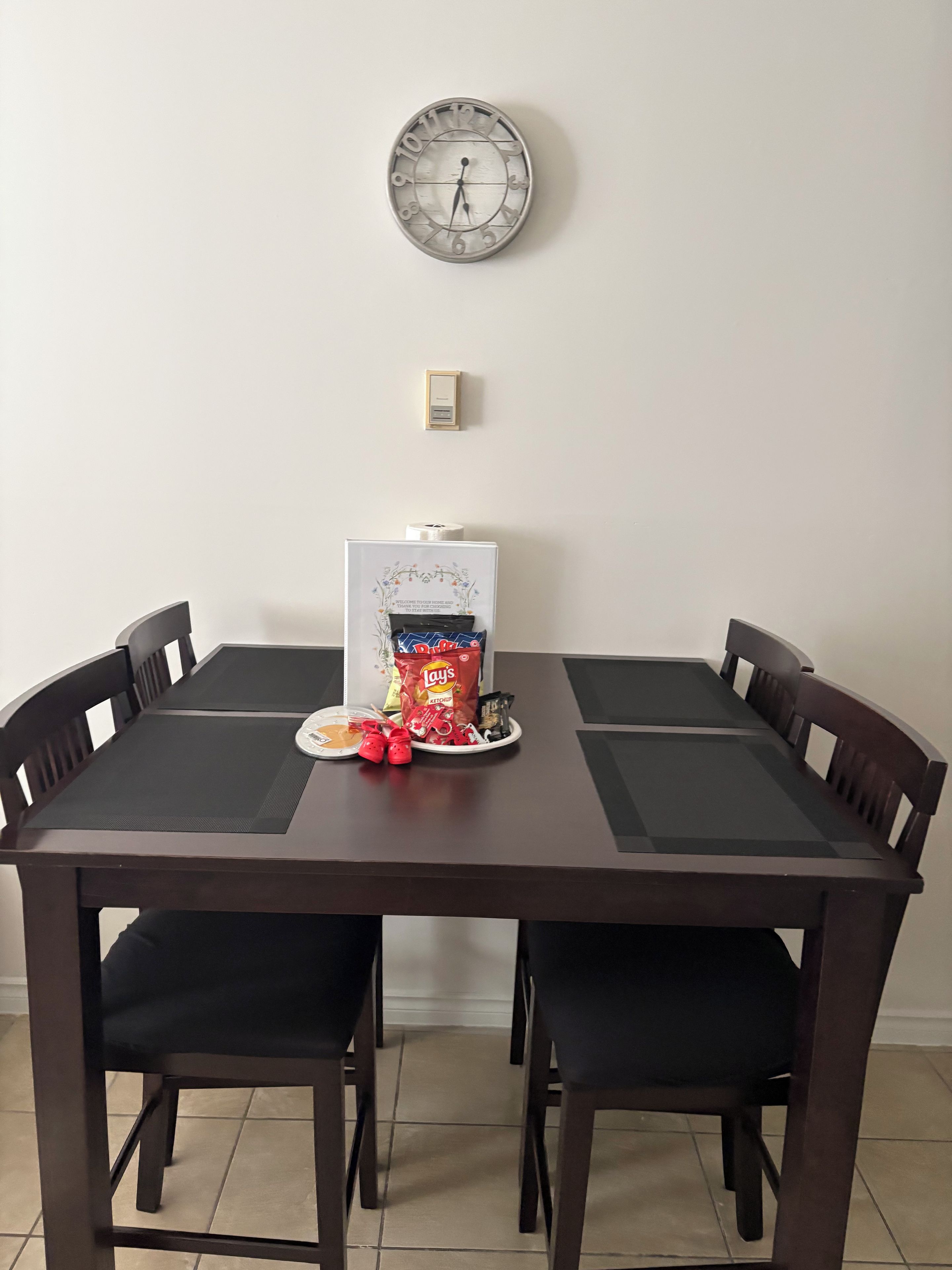 Une table à manger avec une horloge au-dessus, entourée de chaises.