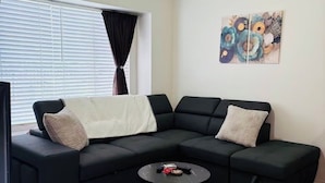 Una sala de estar moderna con un sofá seccional, una mesa de centro y un cuadro en la pared.
