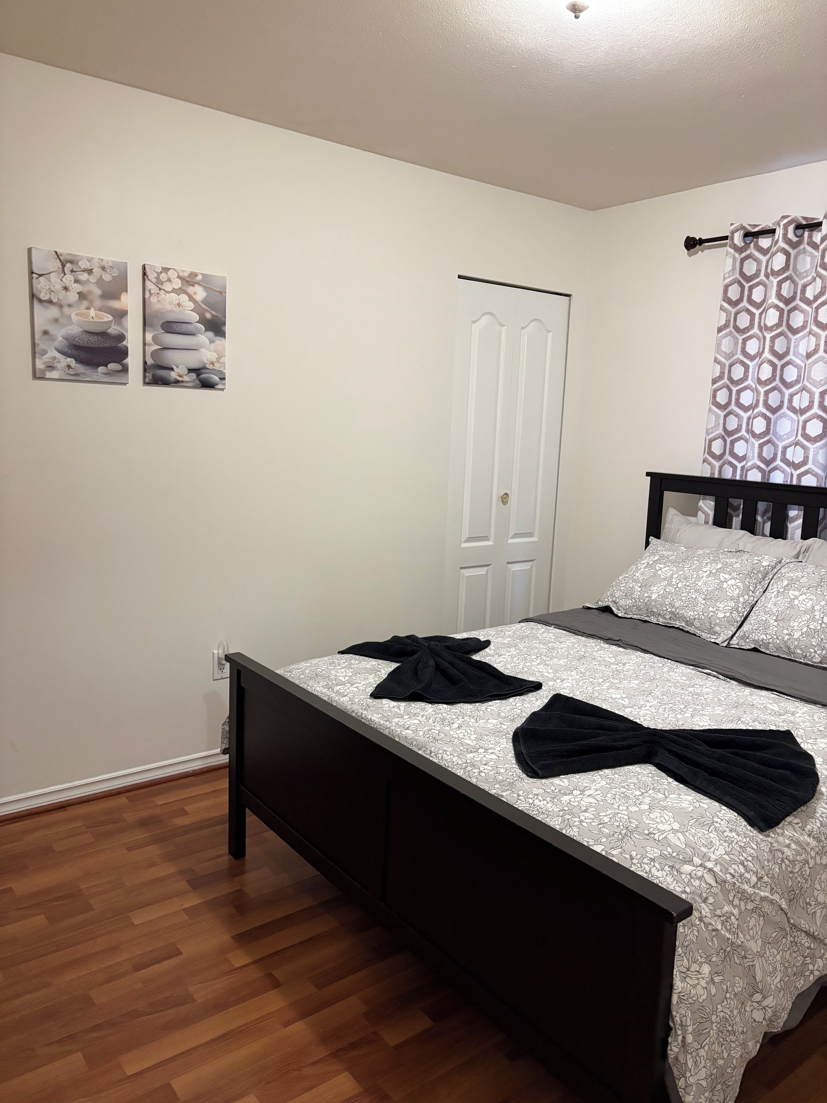 A bedroom with a bed, a door, and two wall-mounted pictures.