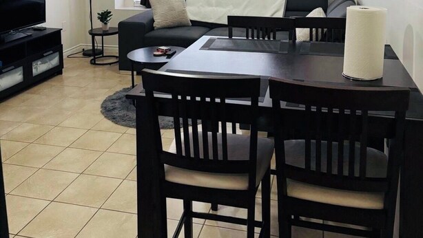 A living room with a TV, sofa, dining table, and chairs.