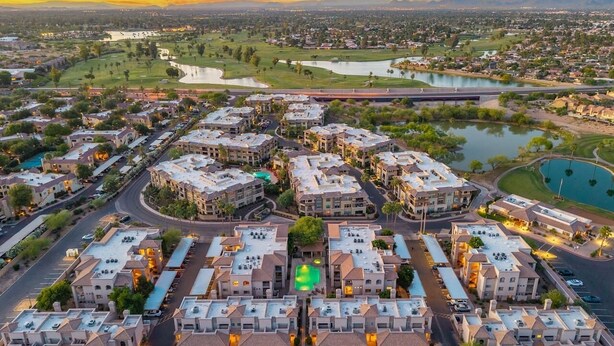 A residential area with apartment buildings, roads, and a lake.