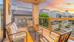 A balcony with a ceiling fan, a sofa, a chair, and a small table.