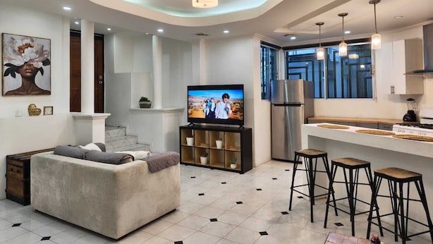 Ein modernes Wohnzimmer mit einer Couch, einem Fernseher und Barhocker.