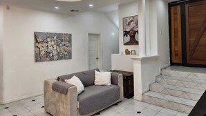 Ein modernes Interieur mit einer Couch, Kunstwerken und einer Treppe, die zu einer Holztür führt.