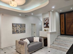 Un interior moderno con un sofá, obras de arte y una escalera que conduce a una puerta de madera.