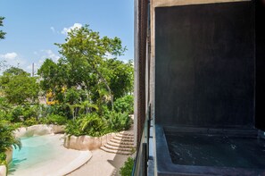 Blick auf einen Pool, umgeben von viel Grün, eine Treppe und ein Gebäude mit dunkler Fassade.