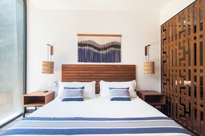 Ein Hotelzimmer mit einem großen Bett, einem Holzkopfteil, zwei Nachttischen, einer gewobenen Lampe und einem Wanddekor.