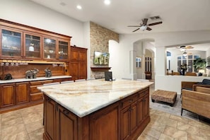 A spacious kitchen with wooden cabinets, a marble island, and a stone backsplash. - Waterfront 3BR Home with Pool ,BBQ Patio & Fire Pit (Glendale)