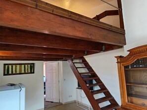 Eine Holztreppe mit Handlauf, eine weiße Tür und ein Schrank mit Glastüren.
