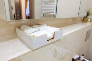 A bathroom with a white towel rack holding four towels, a mirror, and a potted plant on the counter. - Quaint 2-bedroom apartment in the heart of Lublin (Lublin)
