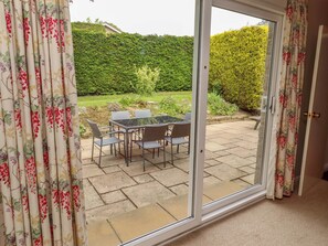 A room with a sliding glass door leading to an outdoor patio with a table and chairs. - Campden (Alnwick)