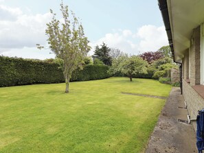 A well-maintained lawn with a small tree and a stone wall. - Campden (Alnwick)