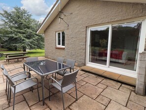 A patio with a glass door, a table, and chairs. - Campden (Alnwick)