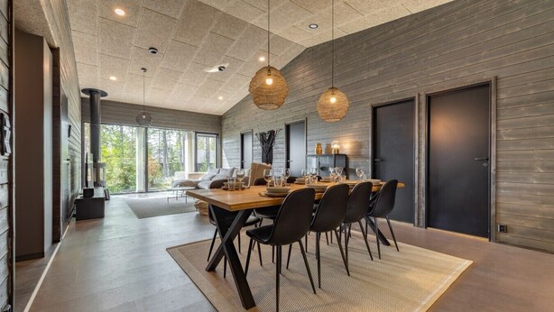 A modern dining area with a wooden table, black chairs, and woven pendant lights.