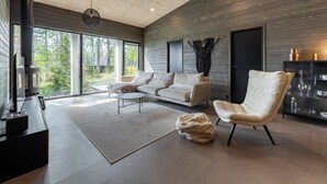 A modern living room with a sofa, armchair, and a fireplace.