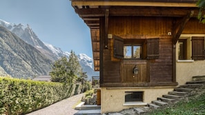 A wooden chalet with a stone staircase, a wooden door, and a window. - Chalet Le Savoy - a newly renovated 5-bedroom chalet in the heart of Chamonix (Chamonix-Mont-Blanc)